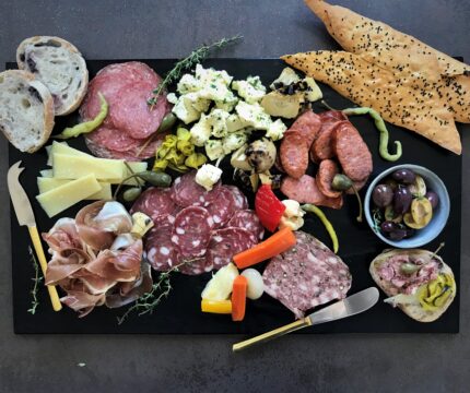 Large charcuterie board. Breads, cheeses, cured meats and olives on display.