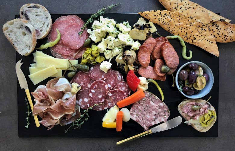 Large charcuterie board. Breads, cheeses, cured meats and olives on display.