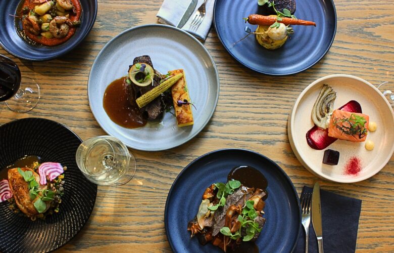 a selection of entres & mains, including salmon, beef, lamb & gnocchi. set on a table with cutlery, glassware & wine